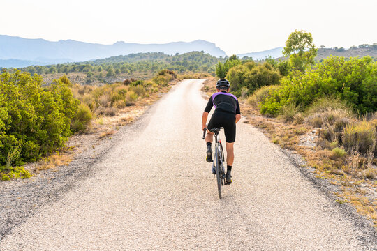 Professional cyclist pedaling on lonely road in the mountain on sunny day