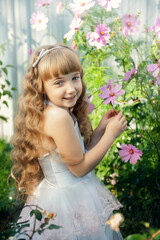 Portrait of a 10-year-old little girl in a blooming rose garden. Cute beautiful cute baby having fun with flowers in the park on a sunny summer day. happy, smiling baby