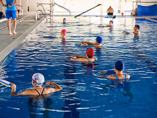Company of people doing exercise with aqua noodles during water aerobics