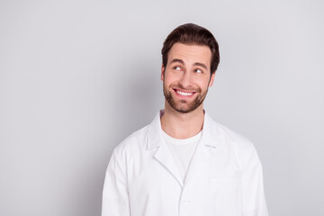 Photo of positive thoughtful young doc man dressed white coat smiling looking empty space isolated...
