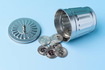 silver bitcoins coming out of a bin on a blue background. cryptocurrency and money.