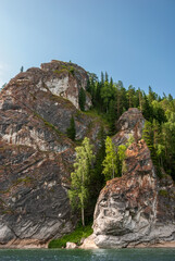 Landscape of Siberia. Kiya River, mountain banks and green forests in the Kemerovo region. Daytime landscape with blue skies and clouds.