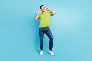 Full body photo of dreamy young happy man look empty space wear headphones isolated on blue color background