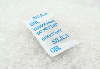 packet of silica gel sands buried in silica crystals. There are caution words "Throw away. Do not eat. Desiccant silica” on the pack.