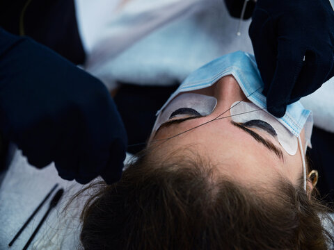 Beautician with thread measuring eyebrows of client