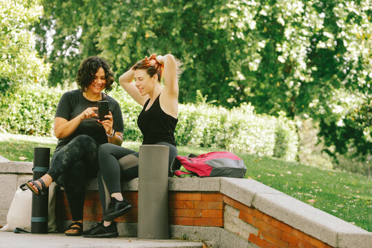 Positive young multiracial women sitting in park before yoga practice - Powered by Adobe