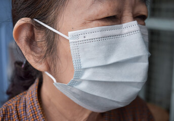 Southeast Asian, Myanmar adult elder woman wearing blue surgical mask or medical mask during...