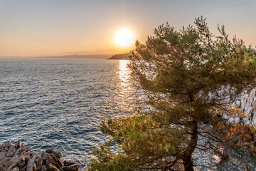 Fototapeta na wymiar Coucher de soleil sur la Côte d'Azur depuis le Cap Ferrat avec vue mer et pins parasols
