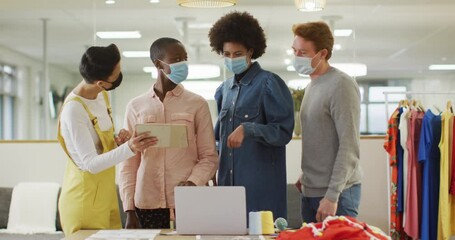 Diverse group of male and female business colleagues wearing face masks and working in office - Powered by Adobe