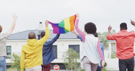 Back view of group of diverse male and female protesters walking with rainbow flag