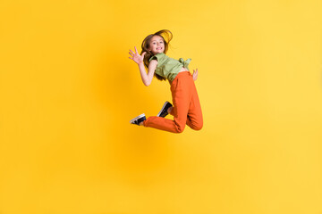 Full length body size photo little girl jumping up careless waving hand isolated vibrant yellow color background