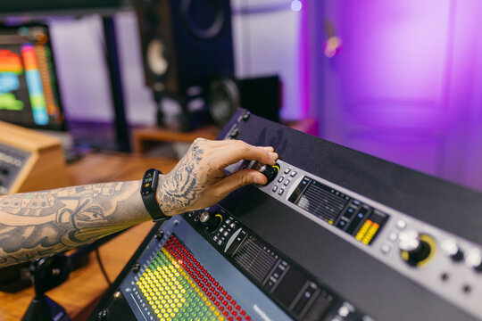 Crop anonymous sound man working with mixing console in music studio