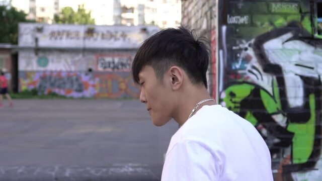 Young Asian man dancing outdoors. Mtransient street dancer, slow motion. Hip hop and breakdancing culture