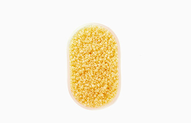 Yellow beads in a plastic box over a white background.
