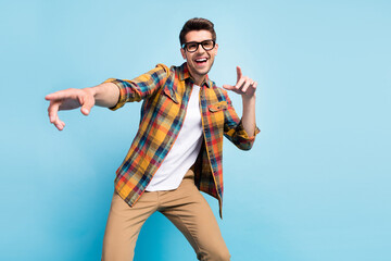 Photo of funky cool young guy dressed plaid shirt smiling dancing pointing fingers isolated blue...