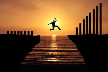 Increase earning and productivity By taking a big risk. Silhouette of a business man jumping over...
