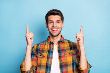 Portrait of attractive cheerful guy pointing forefingers up copy empty space isolated over bright...