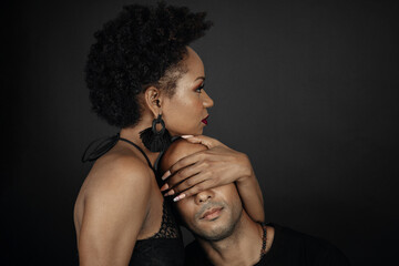 Latin woman and man, girl with afro hair covering boy's eyes on black background. Intimacy concept