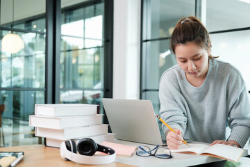 Young collage student using computer and mobile device studying online.