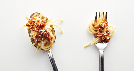 Top view of spaghetti bolognese in a fork and spoonin the light background