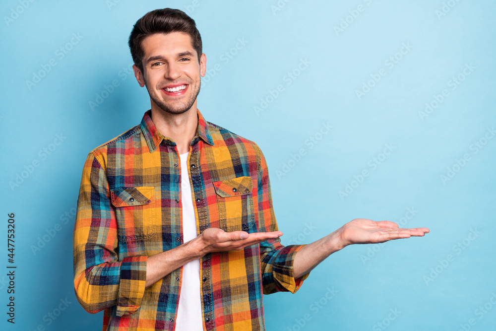 Poster portrait of attractive cheerful guy holding on palms demonstrating copy empty space offer isolated o