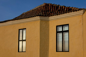 Windows included in an urban setting with yellow textured walls.