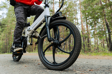 cyclist rides on a bike path in the forest. Riding an electric modern bicycle. Cool fashionable...