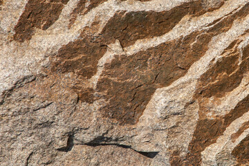 Old uneven granite texture. Brown stone close up, abstract background