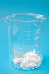 Science laboratory, scientific experiment and lab test concept with dry ice in a glass chemistry beaker isolated on blue background