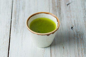 pesto sauce in a gravy boat on white wooden table