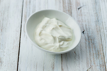 sour cream in a saucepan on white wooden table