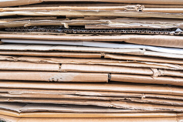 Side view of a stack of folded old used cardboard. Bends and breaks are visible. Background....