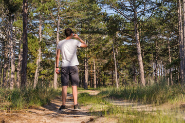 Fototapeta na wymiar Man tourist on a forest path stopped to drink water