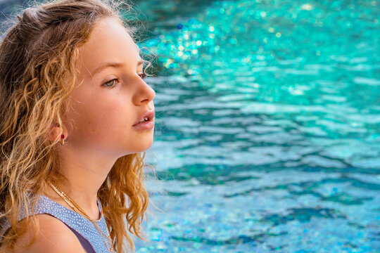 Beautiful young girl sitting near swimming pool and enjoying vacation holidays. High quality photo