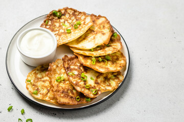 Cheesy zucchini pancakes with yogurt sauce. Space for text.