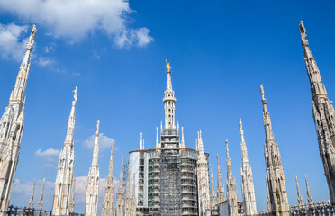 Fototapeta na wymiar Spires and Golden Madonna (Madonnina statue) at the roof of Milan Cathedral (Duomo di Milano) Lombardy region, Italy.