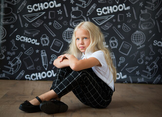 interesting little girl in school clothes against a school board with drawings on the theme of School. School concept. Back to school.	
