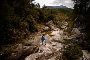 Fototapeta premium high angle view of woman standing on rock along mountain river. Beautiful landscape