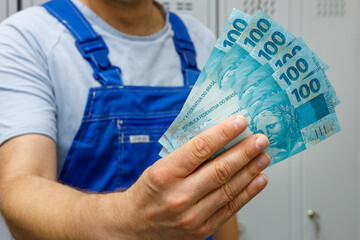 Brazilian worker showing money. Bundle of banknotes , Salaries of professionals and blue collar...