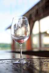 Empty wine glass on a wooden bar outside after the rain