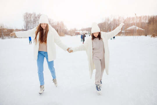 Womans friends learn to skate on ice rink in winter. Concept help, training, healthy recreation, lifestyle