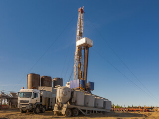 Drilling rig with well cementing equipment in the foreground. Infrastructure, communications and drilling equipment are visible. Cementing unit on a car chassis. Cement storage tanks