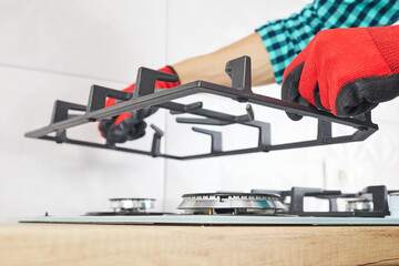 Male hand do installation grill on gas hob in kitchen. Repairs or fix of gas control panel.