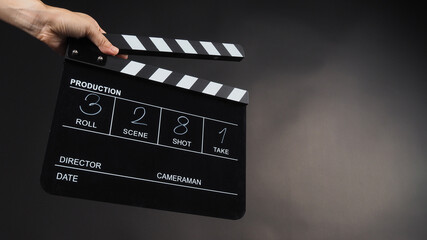 Fototapeta na wymiar A hand is holding black clapper board or movie slate use in video production, movie, film, cinema industry on black background. It has written in number.