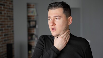 Young man is not healthy and does not feel well. He coughs. His throat and head hurt. The man's eyes are watery