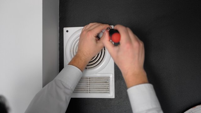 Master fixing ventilation at home. Close up shot hands twirl screw by screwdriver. Unrecognizable man at work