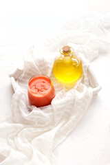 Raw carrot juice and vegetable oil in a glass bottle on a white tablecloth and a wooden tray and background.