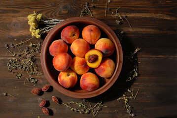 Ripe peaches in a large ceramic dish on wooden brown table Healthy food concept. Top view, plainlay.