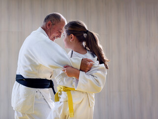 Young yellow belt  judo girl sparring with old sensei - obrazy, fototapety, plakaty