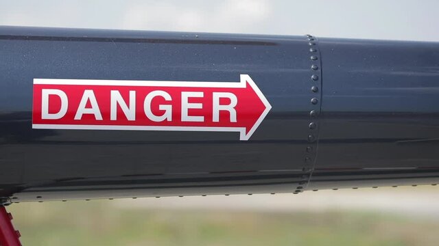 An arrow labeled "danger" is drawn on the glossy metal pipe with rivets, an indicator of the direction of danger.